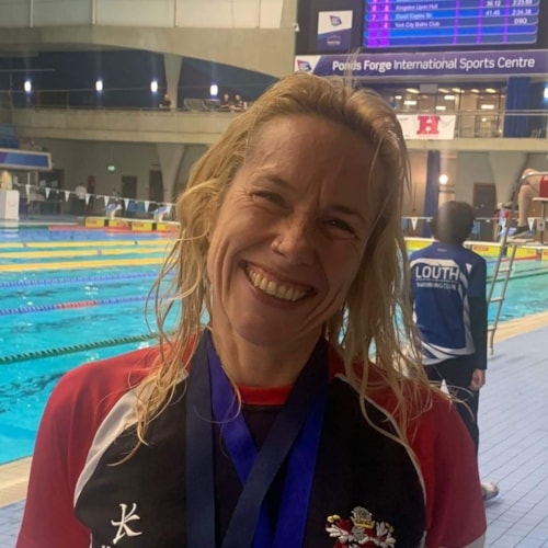A master swimmer at meet with medals around neck